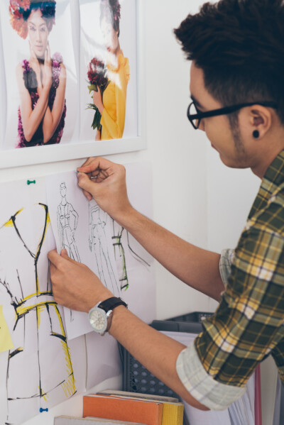 Young designer pinning fashion sketches to the wall