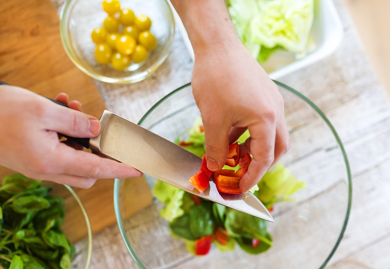 Unrecognizable man preparing ingredients for vegetable salad