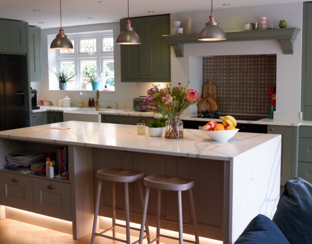 A Shaker style kitchen with large island with marble worktop and pendant lights hanging above