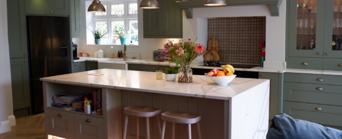 A Shaker style kitchen with large island with marble worktop and pendant lights hanging above