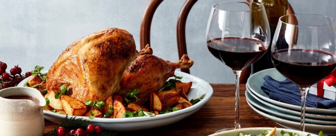 A roast turkey and glass of wine sit on a festively decorated dining table
