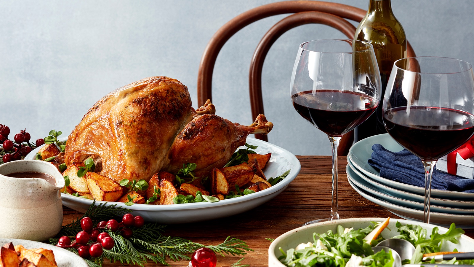 A roast turkey and glass of wine sit on a festively decorated dining table