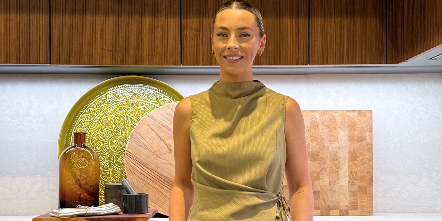 A photo of a woman in a green top, stood in a modern styled kitchen